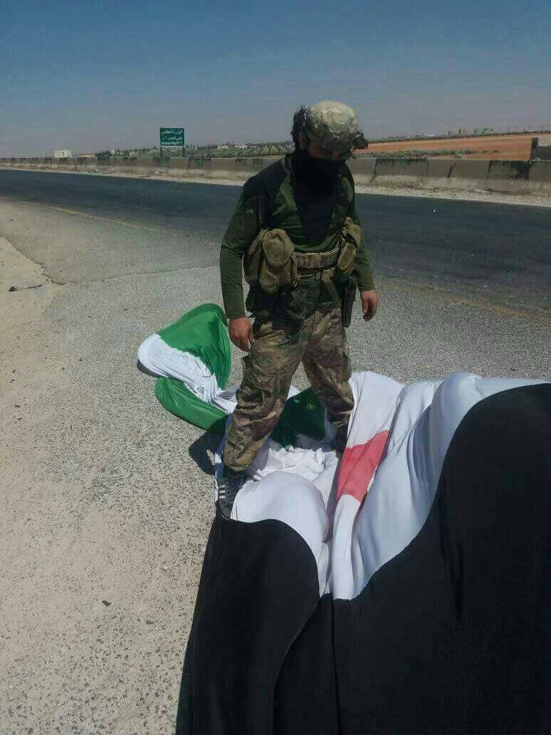 Some Hay'at Tahrir al-Sham fighters step on the Free Syrian Army flag (Syrian Independence Flag) in Saraqib, Idlib Governorate, Syria.