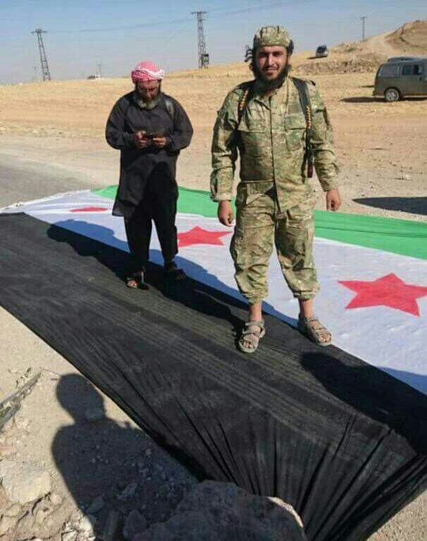 Some Hay'at Tahrir al-Sham fighters step on the Free Syrian Army flag (Syrian Independence Flag) in Saraqib, Idlib Governorate, Syria.