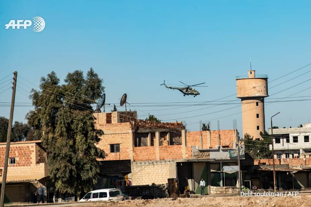 A Russian army helicopter flies over a patrol of US soldiers in the town of Tal Tamr in the northeastern Syrian Hasakeh province on the border with Turkey on January 26, 2020. Delil SOULEIMAN / AFP